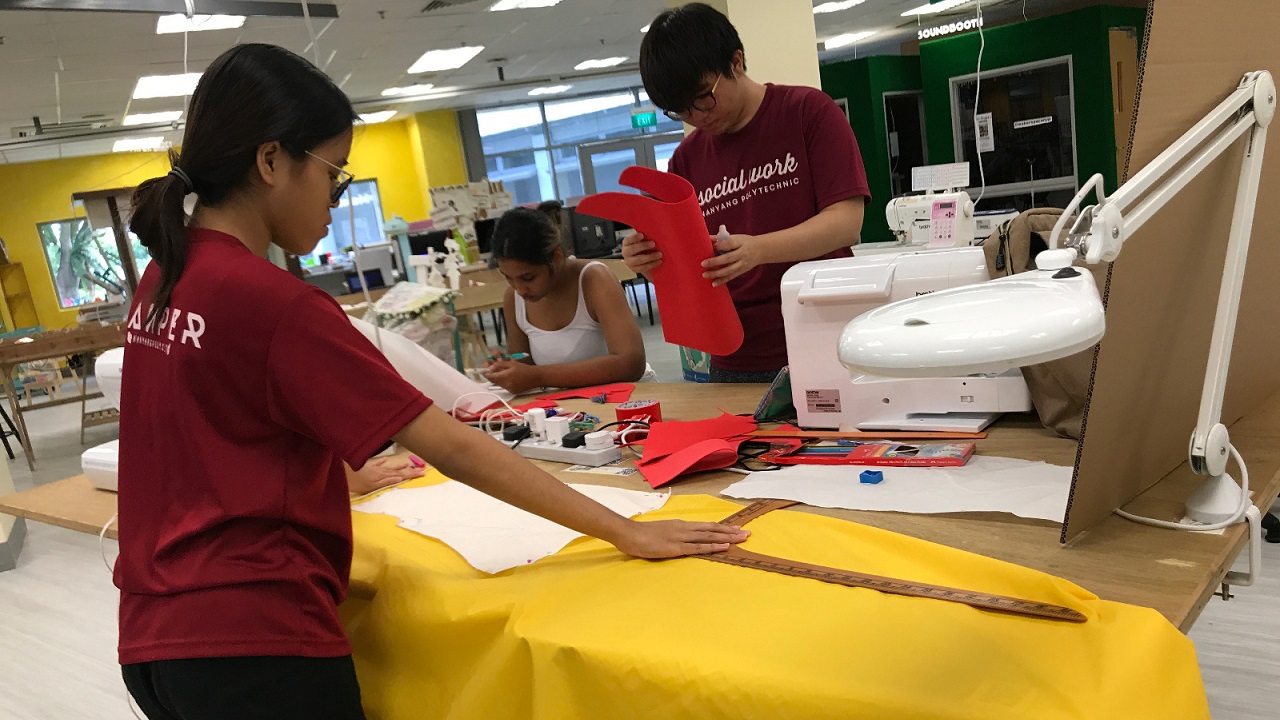 Three individuals collaborating on a craft project at MakerSpaceNYP, showcasing their creativity and teamwork.