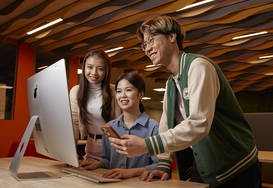 Three youth looking at a desktop monitor